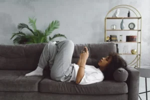 young woman laying on sofa using phone