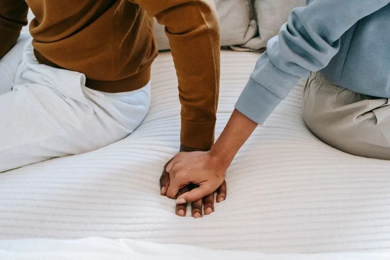 couple holding hands on bed