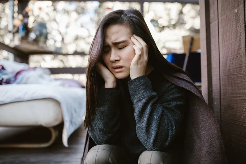 woman with hands on head in pain