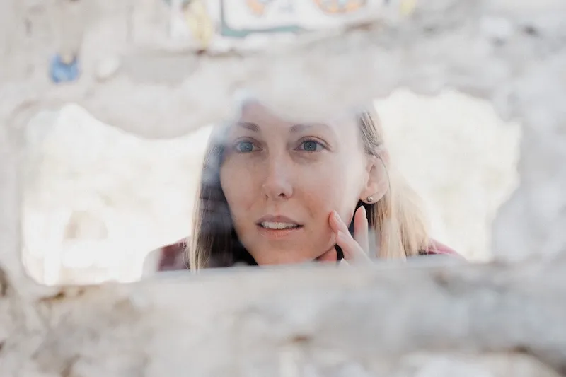 woman looking at face in mirror