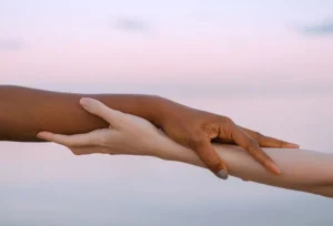 two peoples arms reaching out and holding each other