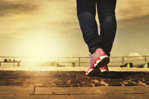 close up of person's feet walking on sunbathed path