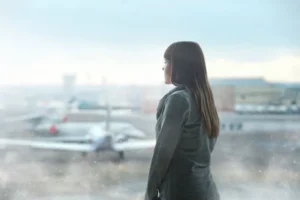 woman looking out at airport airplanes through fogged window
