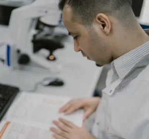 man in science lab researching from journals