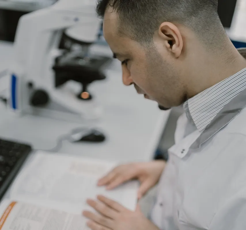 man in science lab researching from journals