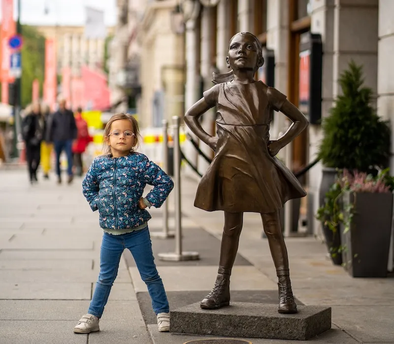 child doing strong pose next to statue