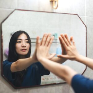 woman reaching out with hands on mirror