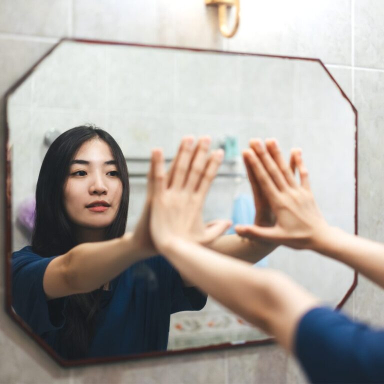 woman reaching out with hands on mirror