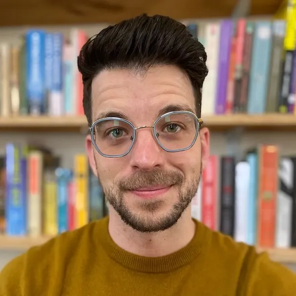 nick hebert smiling in front of bookshelf