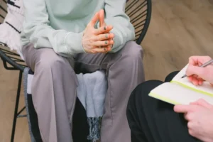 woman in therapy session and therapist writing notes